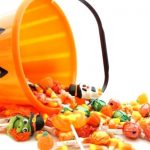 Orange plastic pumpkin basket spilled over with candy pouring out