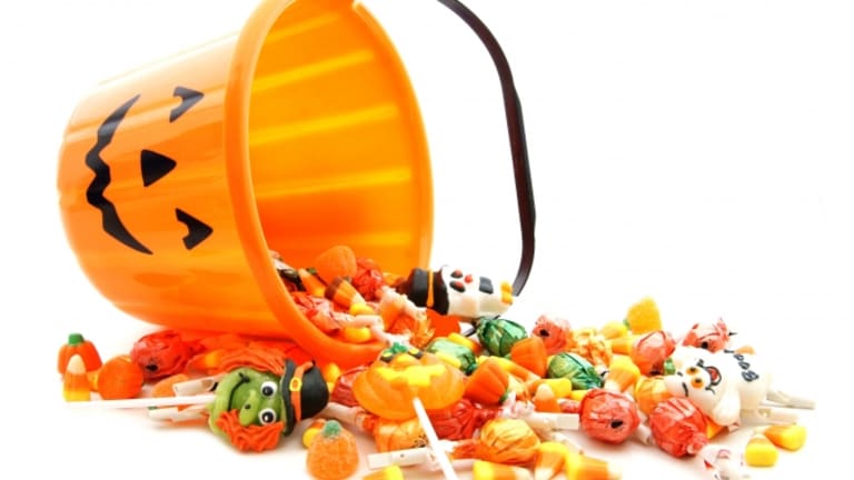 Orange plastic pumpkin basket spilled over with candy pouring out