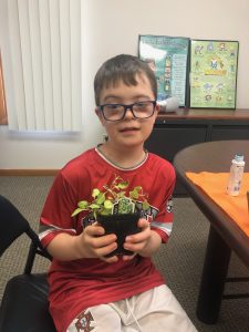 young man holding a plant in a pot