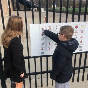 Teacher communicating with student using playground communication board.