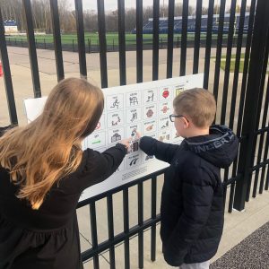 Therapist modeling how to use a playground communication board to student.