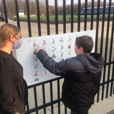 Student using playground communication board Teacher is watching