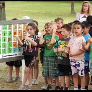 Students standing in front of newly installed playground communication board