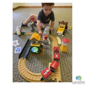 child in therapy session playing with train tracks