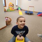 child in therapy playing on a riding toy