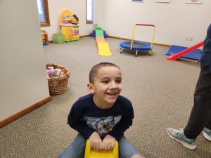 child in therapy playing on a riding toy