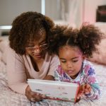 adult and child reading on a bed