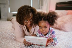 adult and child reading on a bed