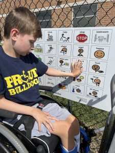 boy in wheelchair using playground communication board